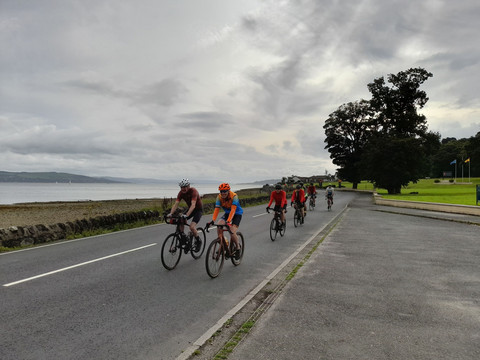 Several cyclists cycling along sea front road 