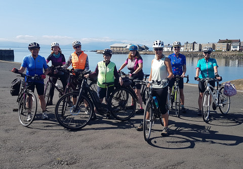 8 cyclists with bikes posing in front of a harbour